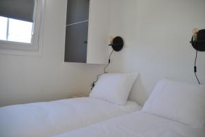 栋堡Minicamping Shalom的一间卧室设有两张白色的床和窗户