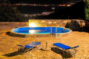 安吉斯乔治亚斯尼拉Pelion Goddess Villas的夜间有两把椅子和一个游泳池