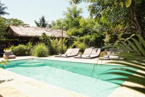 吉利阿尔Musa Villas and Bungalows Gili Air的一个带2把躺椅的游泳池以及1栋房子
