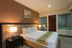 马六甲豪门大酒店的一间卧室,配有一张床和床头灯