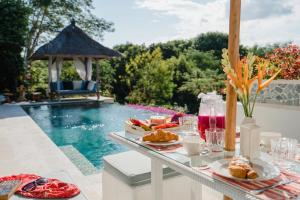 蓝梦岛努沙别墅酒店的游泳池旁的餐桌,供应食物和饮料