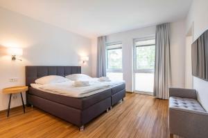 加兹尤瑟多姆Appartement "Seaside" - Oase am Haff的一间卧室配有一张床、一张沙发和窗户。