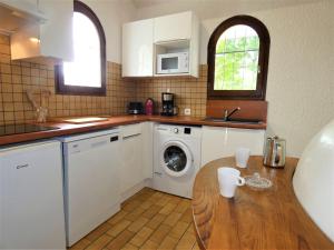 米米藏Holiday Home Le Fournil by Interhome的厨房配有洗衣机和木桌。