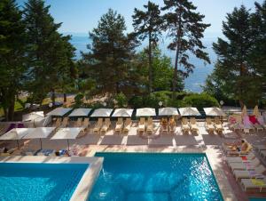 洛夫兰Hotel Excelsior - Liburnia的一个带椅子和遮阳伞的游泳池以及大海