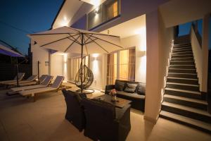 卡斯特罗诺维Villa Sunset的房屋设有1个带沙发和遮阳伞的庭院