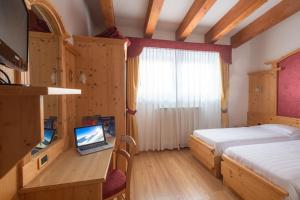 帕苏德尔托纳莱安格鲁酒店的一间卧室配有一张床和一张桌子上的笔记本电脑