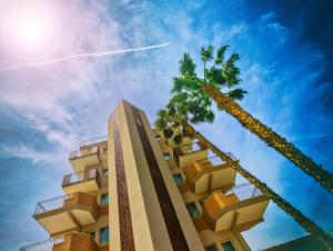 阿尔巴·阿德里亚蒂卡Almaluna Hotel & Resort的两棵棕榈树旁边的高楼