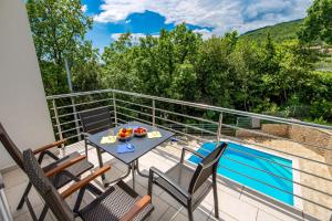 奥帕提亚Villa Dragi with Pool, Sauna, & Whirlpool的一个带桌椅的阳台和一个游泳池