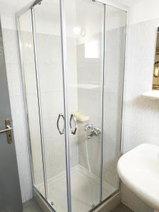 波帝卡Sunset Apartments的一个带水槽的浴室内的玻璃淋浴间