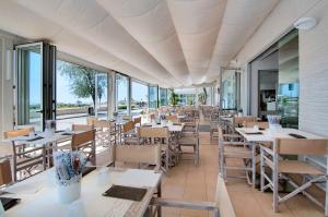 卡奥莱Hotel Levante的餐厅设有桌椅和窗户。