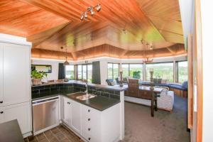 坎布里奇Lakeview Lodge Karapiro的一间厨房和一间带木天花板及桌子的客厅