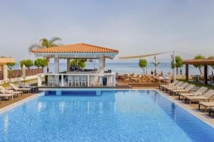 依克希亚Villa Di Mare Seaside Suites的一个带椅子和凉亭的度假村游泳池