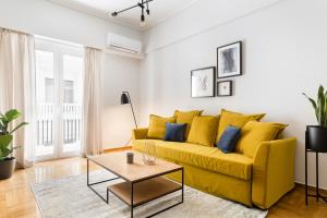 雅典Central Cozy Apartments in Plaka by UPSTREET的客厅里一张黄色的沙发,配有桌子