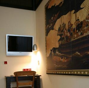 海德堡HIP Hotel的一间配有电视的房间,墙上挂有绘画作品