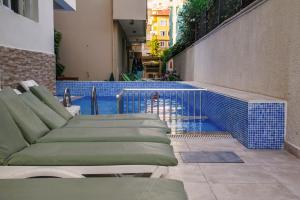 阿拉尼亚Aysev Hotel的一座带躺椅的游泳池,位于大楼旁