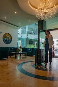利马米拉弗洛雷斯科隆酒店的带着行李站在大堂的女人