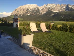 巴德米滕多夫Alpenapartments Steiermark的两把椅子坐在草坪上,背靠山