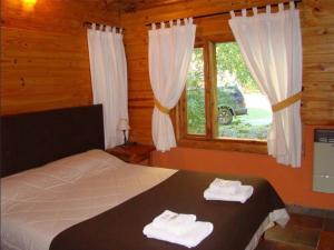 圣卡洛斯-德巴里洛切恩尔科拉宗德尔博斯克山林小屋的一间卧室配有床和带毛巾的窗户。
