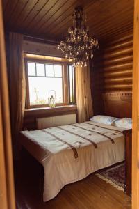 Gourri*2 bdr log house /mountains/Queen bed/fireplace的一间卧室配有一张带吊灯和窗户的床。