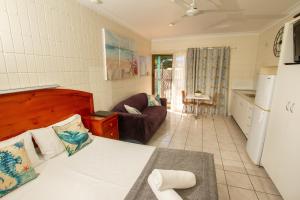 Picnic BayTropical Palms Resort & 4WD Hire的一间卧室配有一张床和一个沙发