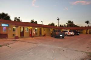 CalexicoCalifornia Suites Motel的加油站,停泊在停车场的汽车