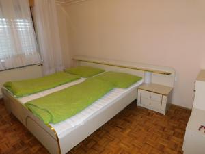 Videm pri PtujuHaus Videm的一间卧室配有一张带绿色床单的床和一张桌子
