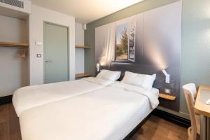 锡河边的圣奥班B&B HOTEL Dieppe的一张大白色的床,位于带桌子的房间