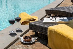 基安蒂格雷夫La Rimbecca Greve in Chianti的两杯葡萄酒和一张桌子上的书,旁边是游泳池