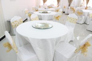 马斯喀特Al Hussam Hotel Apartments的一排桌子和椅子,配有白色的桌布