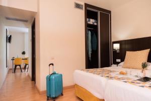 帕拉莫斯Aparthotel Ona Palamós的酒店客房,带一张床和行李箱