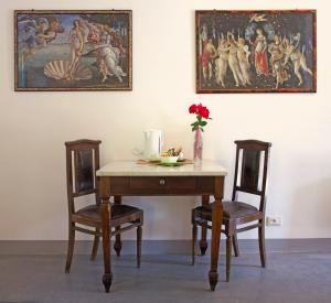 皮亚琴察Corte La Volta的一张桌子,上面有两把椅子和花瓶