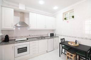 里斯本塞特里奥斯公寓，靠近动物园里斯本/免费无线网络的厨房配有白色橱柜和黑色桌子