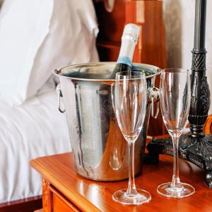 莱瑟姆-圣安妮The Queens Hotel的桌子上装有一瓶葡萄酒的桶和两杯