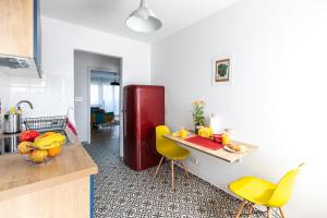 萨格勒布Blue Sky Apartment的厨房配有黄色椅子和红色冰箱