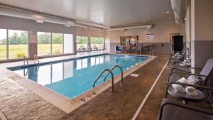 OlneyBest Western Plus Parkside Inn & Suites的游泳池位于酒店房间,周围设有椅子