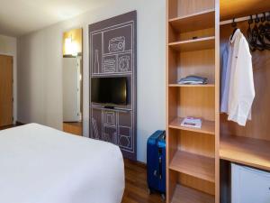 圣若泽ibis Sao Jose的酒店客房设有床、电视和书架。