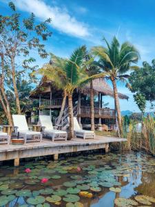 珍南海滩Kunang Kunang Heritage Villas的棕榈树、椅子和池塘的度假胜地