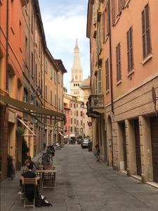 摩德纳Modena Charme Sant'Eufemia的街道上,有楼房,有人坐在桌子上