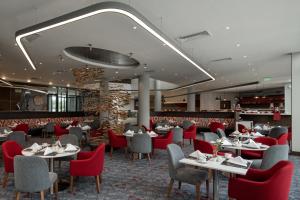 达累斯萨拉姆Crowne Plaza - Dar Es Salaam, an IHG Hotel的用餐室配有桌子和红色椅子