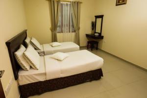 锡卜Jarzez Hotel Apartments Al Hail的酒店客房设有两张床和窗户。