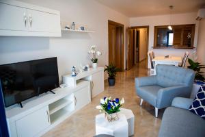 滨海罗克塔斯Apartment las sirenas WiFi 100 Mb的客厅配有平面电视和蓝椅。