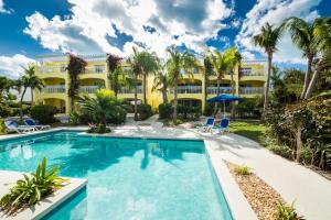 格雷斯湾格雷斯湾公寓式酒店的棕榈树黄色建筑前的游泳池