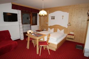 富尔普梅斯格本霍夫高山农场的一间卧室配有一张床、一张桌子、一张床和椅子