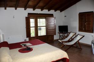 哈兰迪雅·德·拉·维尔Complejo Rural La Coronilla的一间卧室配有一张床、两把椅子和电视