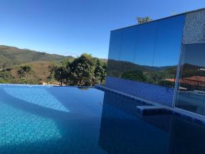 欧鲁普雷图Hotel Recanto do Ouro - Antigo Recanto da Serra的一座带游泳池的建筑,背景是群山