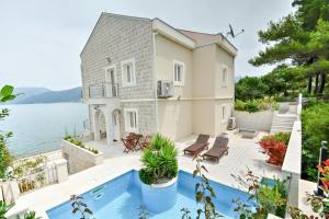 克拉西奇Villa Leut Montesol Tivat Krasici的水边的房屋,设有游泳池