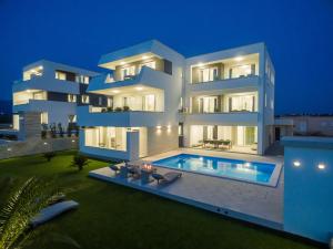 诺瓦利娅Apartments & Rooms Pool Villas Maris的一座白色的大建筑,晚上设有游泳池