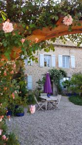 La Bastide-lʼÉvêqueChambres d’hôtes du Presbytère的大楼前的野餐桌和雨伞