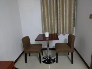 帝力CHONG TI HOTEL的窗户间里的一张桌子和两把椅子