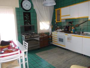 Nuova GibellinaGibellina Home的厨房铺有绿色瓷砖,墙上设有时钟